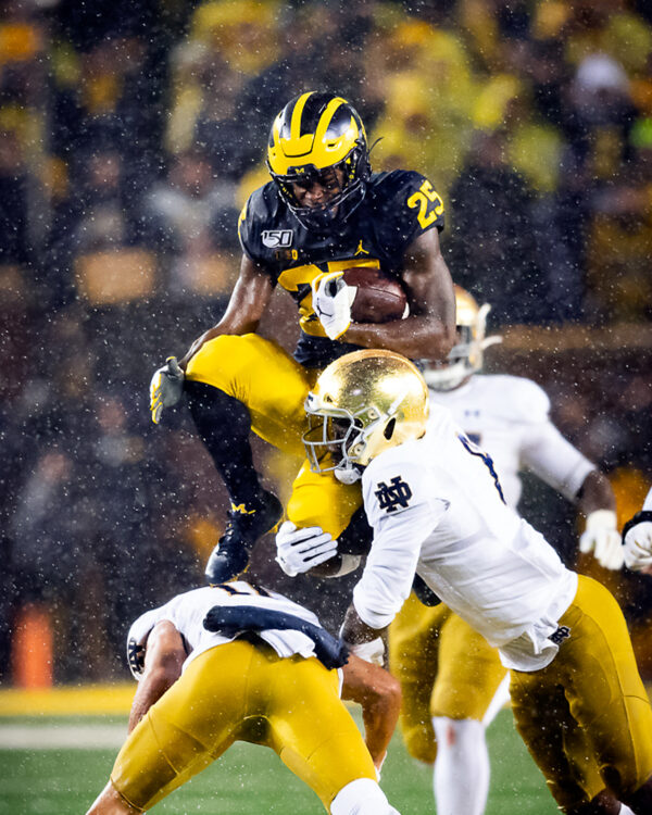 Michigan running back Hassan Haskins hurdles over a charging Notre Dame player