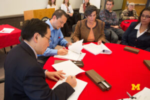 Image of individuals seated at a table signing paperwork.